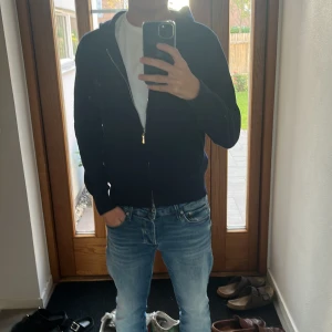 Mörkblå tröja med dragkedja - Snygg mörkblå hoodie med huva och snörning, perfekt för chill dagar. Tröjan har dragkedja framtill och två fickor. Materialet är lite varmare och stickat. Passformen är normal och ärmarna är långa. Enkelt och stilrent plagg för din garderob. Pris kan diskuteras😀🙌