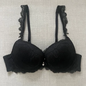 svart spets bh  - Supersnygg svart push-up bh med spetsdetaljer och små rosetter på axelbanden. Axelbanden är justerbara. Helt ny, aldrig använd. Storlek 80a. Har även en helt ny likadan i vit, fråga så skickar jag bild på den med! 