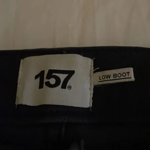Svarta bootcut jeans från 157, S - Svarta jeans från 157 i bootcut-modell med full längd. Snygg klassisk femficksdesign och silverfärgade nitar. Jeansen har låg midja och är gjorda i mjukt denimtyg som sitter skönt hela dagen. Perfekt för dig som gillar en stilren look med lite extra edge.