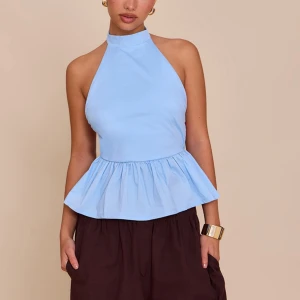 Ljusblå ärmlös halterneck topp - Supersöt ljusblå halterneck topp med volang nertill och öppen rygg. Toppen har hög hals och smala band i ryggen som ger en snygg och luftig look. Perfekt för varma dagar och enkel att styla med både jeans och kjol. Aldrig använd!!