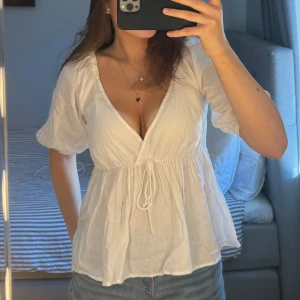 Vit topp med volang och rosett - Säljer denna söta topp från Bik Bok. Endast använd en gång och i super fint skick. Har ett litet hål från en säkerhetsnål vid urringningen som man kan se på bilden. Storlek S, passar M också. 150 kr + frakt. Vid fler frågor, etc skriv privat 🩷🙌🏼☀️🏄🏽‍♀️💐🍋‍🟩