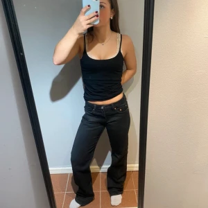 Svarta Weekday Arrow Low Straight Jeans - Säljer ett par svarta Weekday Arrow Low Straight Jeans med låg midja och raka ben. Materialet är jeans i bomull med en snygg mörk finish.