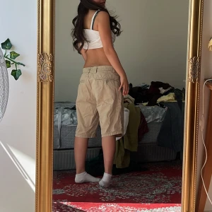 Beiga baggy shorts från Etirel - Säljer ett par beiga shorts från Etirel med baggy passform och midwaist. De har klassisk design med fickor fram och bak, bälteshällor och knapp samt dragkedja. Materialet är mjuk 100% bomull som känns skönt mot huden. Storleken är xs herr