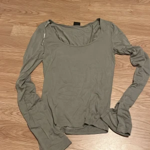 Grön långärmad topp från Gina Tricot - En grön långärmad topp från Gina Tricot med slits i ärmarnas slut. Inte kommit till användning mer än några få gånger🩷