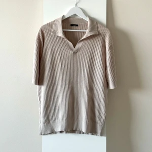 Beige ribbad tröja från Massimo Dutti - Ny och oanvänd beige kortärmad tröja från Massimo Dutti. Mjuk material med ribbad struktur och öppen krage. Perfekt för sommar eller lager på lager. 74% bomull, 26% lin. Storlek XXL.  Nypris: 800kr