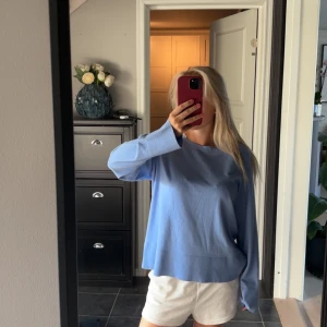 Ljusblå stickad tröja med lång ärm - Säljer en chill ljusblå stickad tröja med rund hals och långa ärmar. Tröjan har en loose passform och bred ribbad kant nedtill och vid ärmslut. Perfekt att slänga på sig när det är lite kyligt ute.