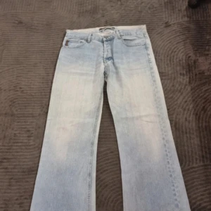 Ljusblå bootcut jeans från Cottonfield - Snygga ljusblå jeans från Cottonfield med klassisk femficksdesign och bootcut-ben. Jeansen har en normal passform och är tillverkade i jeansmaterial med ljus tvätt. Perfekta för dig som gillar retrovibbar och avslappnad stil.