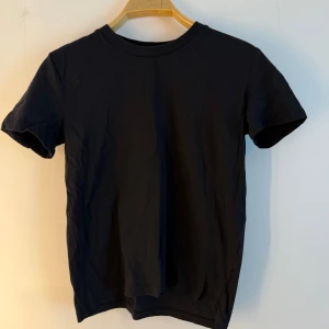 Svart T-shirt  - Svart t-shirt med rund hals och korta ärmar. Passar perfekt till vardags eller fest. Storlek S 