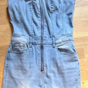 Axelbandslös denim oncie byxdress - Ny snygg ljusblå denim byxdress med dragkedja framtill och markerad midja Det är en tight modell med lite utställda ben Den har fickor fram & bak, hällor för skärpet och den är i ett stretchigt denim tyg Storlek Medium/38 från Shein Den är helt ny i jättefint skick, bara testad!