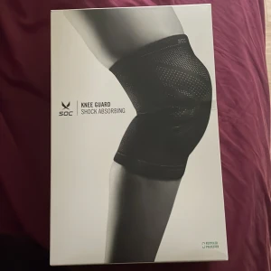 Svarta knäskydd från SOC - Säljer ett par svarta knäskydd från SOC med shock absorbing-funktion. De är tillverkade av återvunnen polyester, polyuretan, polyamid, silikon och gummi. Knäskydden har en tight passform och diskret mönster för extra stöd och komfort vid träning.