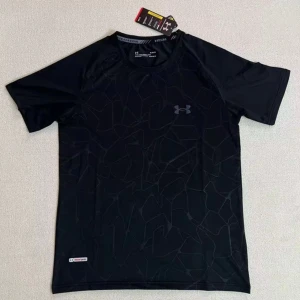 Svart tränings-tshirt Under Armour - Svart t-shirt från Under Armour med diskret geometriskt mönster och logga på bröstet. Kortärmad och tillverkad i lätt polyester som andas, perfekt för gymmet eller löprundan. Snygg, sportig passform och cool design.