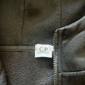 Svart hoodiejacka med goggles från C.P. Company - Säljer en svart hoodiejacka från C.P. Company 