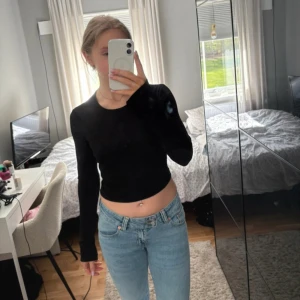 Svart croppad topp med öppen rygg - Säljer en svart långärmad topp som är croppad och har en snygg öppen rygg med snörning. Toppen är ribbad och har en rund halsringning framtill. Perfekt för dig som gillar coola detaljer och vill sticka ut lite extra. Ens snöret har gått upp (bild 3) men syns ej när man knyter.