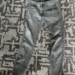 Replay Anbass grå jeans slim fit - Snygga Replay Anbass jeans i grå tvätt med klassisk femficksdesign och Replay-logga på fickan. Slim fit.
