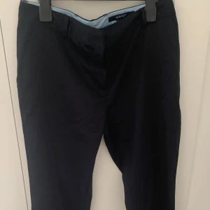 Svarta kostymbyxor från GANT - Snygga svarta kostymbyxor från GANT med klassisk rak passform och mid-waste. Byxorna har fickor i sidorna och är tillverkade i bomull.  Perfekta för en clean och stilren look. Original pris för dem var 1 500 kr, säljer för mindre än hälften.