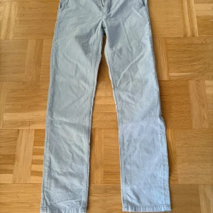 Ljusblå chinos från Gant, 158/164 - Snygga ljusblå chinos från Gant i storlek 158/164. Byxorna har klassisk rak passform, sidofickor fram och knäppning bak. Tillverkade i mjuk bomull, perfekta för dig som gillar stilrena och fräscha looks. Passar dig som är 13-14 år.