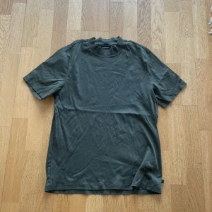 Mörkgrön t-shirt från J.Lindeberg - Säljer en stilren mörkgrön t-shirt från J.Lindeberg. T-shirten har klassisk passform, rund halsringning och är tillverkad i mjuk bomull. Perfekt för en enkel och clean look.