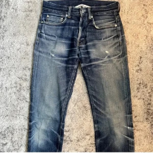 Blå jeans från Our Legacy med slitningar - Säljer ett par klassiska blå jeans från Our Legacy med raka ben och knappar i gylfen. Jeansen har en snygg tvätt med slitningar och ljusare partier på låren och knäna. Perfekta för dig som gillar en tidlös denimlook. Helt galna jeans som är ovanliga, samt galen tvätt och detaljer. Ny priset ligger på cirka 4000kr tror jag. Den enda defekten skulle jag säga är där man sätter i knappen på tredje bilden, Man kan fortfarande knäppa och den åker inte ut så man får tolka det hur man vill