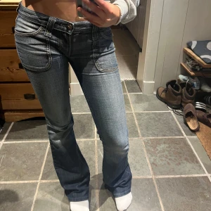 Blå low bootcut jeans från frankie B - Säljer skitsnygga jeans från frankie B. De är väl använda men i mycket bra skick, lite längst ner man på bilden. Det syns inte när man har de på sig. Midjan var 27 från början men vi gjorde så man kan justera midjan, ni kan se på en bild. Jag har vanligtvis 24/25 i midjan och de syns inte att man justerat den som ni ser på bilden har jag har de på mig. Jag är 167 lång skulle säga att de passar någon som är mellan 165- 170 lång beroende påhur man vill att de sitta. Har mi frågor hör av er❤️❤️