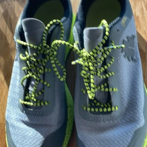 Gråa och limegröna löparskor från Icebug - Säljer ett par gråa Icebug Orbit3 W BUGrip GTX med limegröna detaljer och snörning. Skorna har grov sula med metalldubbar för extra grepp, perfekta för löpning på hala underlag. Insidan är fodrad i limegrönt tyg.