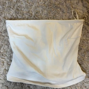 Vit tubtopp - Säljer en enkel och stilren vit tubtopp. Perfekt att matcha med jeans eller kjol för en clean look. Gjord i mjukt och stretchigt material som sitter bekvämt på kroppen.