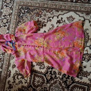 Rosa blommig klänning med puffärm - Säljer en rosa klänning med blommigt mönster och korta puffärmar. Klänningen har knappar framtill och en lätt utställd kjol. Perfekt för sommarens alla tillfällen!