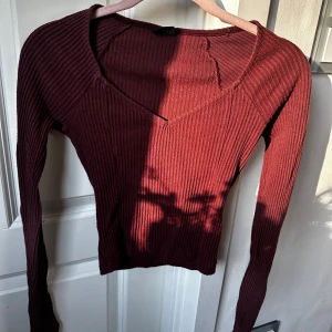 Vinröd ribbad tröja från Gina Tricot - Säljer en vinröd ribbad långärmad tröja från Gina Tricot i storlek XS. Tröjan har v-ringning och är figurnära med croppad passform. Perfekt för lager-på-lager eller som den är till jeans eller kjol.
