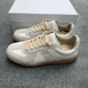 Maison Margiella Gats - Snygga sneakers i vitt och beige med ovandel i skinn och mocka. Skorna har klassisk snörning, rund tå och platt sula i gummi. Perfekta för en stilren och avslappnad look.                                              Helt nya använda typ 3 gånger var inte min stil