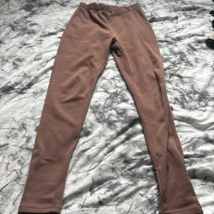 Bruna leggings från Lindex - Säljer ett par bruna leggings från Lindex i storlek 170. De har en enkel och stilren design med resår i midjan och är tillverkade i ett mjukt och stretchigt material. Perfekta för en avslappnad och bekväm stil.