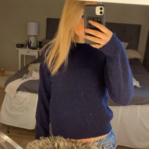 Mörkblå stickad tröja - Mysig mörkblå stickad tröja med rund halsringning och långa ärmar. Tröjan är perfekt att matcha med jeans eller kjol. Passformen är normal och materialet känns mjukt och bekvämt.
