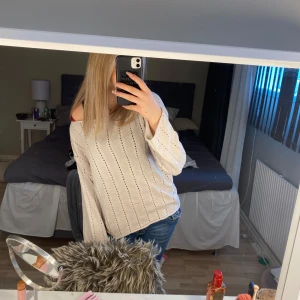 Beige stickad tröja med hålmönster - Säljer en beige stickad tröja med diskret hålmönster och rund halsringning. Tröjan har lång ärm och en avslappnad passform, perfekt att styla med jeans eller kjol. Supermjuk och enkel att matcha med olika outfits.