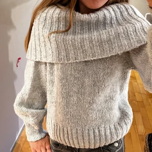 Grå stickad tröja med stor krage från Gina Tricot - Mysig grå stickad tröja från Gina Tricot med stor, bred krage som kan vikas ner. 😃Tröjan har lång ärm och ribbade muddar vid ärmslut och nederkant. ❤️Perfekt för att styla till jeans🩷😇