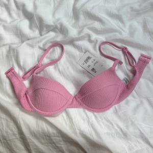 Rosa bikini-set från soc - Säljer en söt rosa bikini från soc. Överdelen har vadderade kupor och justerbara axelband, medan underdelen har en enkel, ribbad design. Perfekt för stranden eller poolen i sommar!