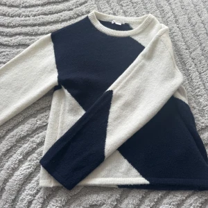 Svartvit stickad tröja med grafiskt mönster - Säljer en stickad tröja i svart och vitt med ett coolt grafiskt mönster. Tröjan har rund halsringning och långa ärmar. Perfekt för dig som gillar stilrena kontraster och vill ha något unikt i garderoben.