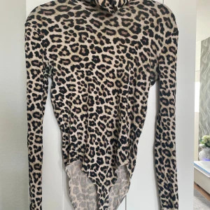 Leopardmönstrad body - Säljer en snygg body med leopardmönster. Bodyn är i stretchigt material och har en tight passform. Perfekt för dig som vill sticka ut med ett djurmönster i garderoben.