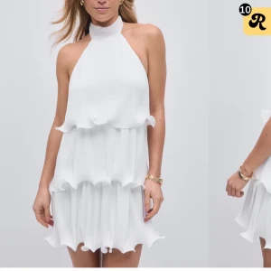 Vit halterneckklänning med volanger - Superfin vit kortklänning med halterneck och volangdetaljer i flera lager. Knytning i nacken och lätt, luftig känsla. Perfekt för sommarens alla tillfällen. Helt slutsåld. 