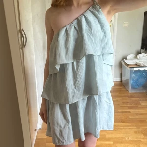 Enaxlad volangklänning - Enaxlad kort volangklänning i ljusblå. Justerbar och knytes vid axeln 💕 jag är 167cm o bär vanligtvis s