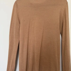 Beige långärmad tröja - Säljer en enkel och stilren beige långärmad tröja. Tröjan har en rak passform och är tillverkad i ett mjukt material som passar perfekt till vardags. Perfekt basplagg att ha i garderoben. Från hm i merinoull 