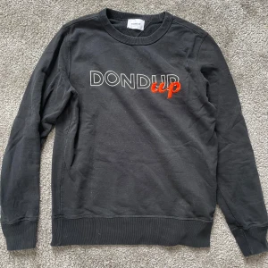 Svart sweatshirt från Dondup - Säljer en svart sweatshirt från Dondup med texten 'DONDUP up' broderad på bröstet i vitt och rött. 