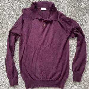 Vinröd långärmad tröja från John Henric - Säljer en vinröd långärmad tröja från John Henric. Tröjan har krage och en knapp framtill, samt ribbade muddar vid ärmslut och nederkant. Perfekt för lager-på-lager och stilrena outfits.