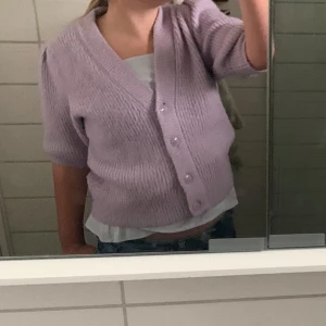 Lila ribbad kofta från Monki - Säljer en söt lila kofta från Monki i storlek S. Den är ribbad med trekvartsärmar och har knappar framtill. Perfekt för en mysig dag eller en avslappnad stil. 💜