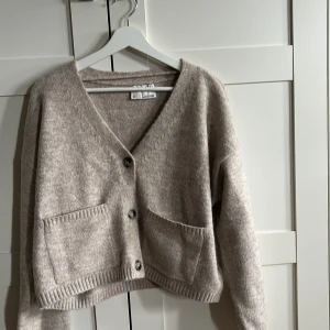 Beige stickad kofta från Nelly  - Mysig beige stickad kofta från Nelly med v-ringning och knappar framtill. Säljer denna jättefina beiga kofta. Endast använd en gång. 💕Nypris 599kr men säljer för 300kr