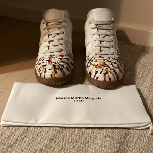 Maison Martin Margiela sneakers med färgstänk - Unika sneakers från Maison Martin Margiela med ett konstnärligt färgstänksmönster i flera färger. Skorna har en klassisk snörning och rund tå. Perfekta för dig som vill sticka ut med stil.