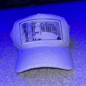 Vit keps med tryck - Snygg vit keps med ett unikt tryck på framsidan. Kepsen har en klassisk design med nätpaneler baktill för extra ventilation. Perfekt för en avslappnad stil.