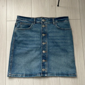 Jeanskjol med knappar från Fonz - Snygg jeanskjol från Fonz med knappar framtill och klassiska femficksdetaljer. Perfekt för en avslappnad stil. Tillverkad i hållbart denim.