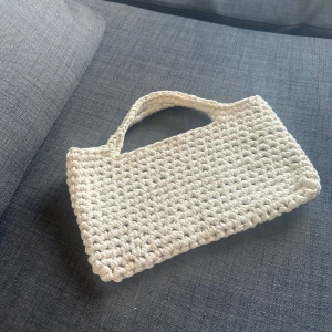 Virkad väska - Säljer en liten handvirkad väska i återvunnet matterial. Uppskattar den till att vara ca 25x10 cm. Billig då den är en ny modell jag testat. 