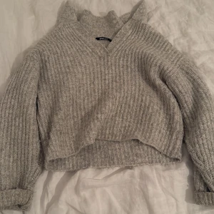 Grå stickad tröja  - Säljer en stickad grå tröja från Gina tricot som är v ringad. Den är lite nopprig men kan nog fixas med en nopp maskin!
