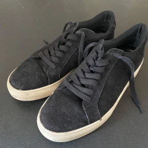 Svarta sneakers från Bond - Snygga svarta sneakers från Bond med en klassisk design. Skorna har en rund tå och snörning framtill. De är tillverkade i mocka med en vit sula som ger en stilren kontrast. Perfekta för en avslappnad look. Storlek 41 men passar även 42. Nypriset var ca 1400 samt att dem tvättas innan dem skickas.