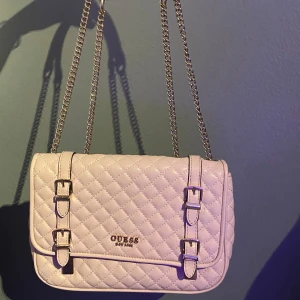 Guess väska - En guess väska som jag har haft i nått år, nyköpt för cirka 1500kr. Den är i fint skick inte så mycket att klaga på, den är i ljusrosa med guld ditaljer. 