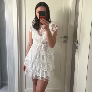 Vit studentklänning med spets - Söt vit spetsklänning med volanger och kort ärm🌸 V-formad fram och öppen ryggdetalj🤍 Köpt från Sellpy i nyskick men jag ska ha en annan klänning på studenten. Perfekt till studenten eller skolavslutning🫧🌤️✨